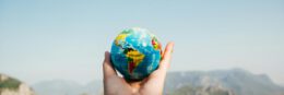 Hand holding a globe against a mountain background symbolizing travel and exploration.